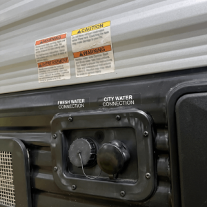 Checking water connections and tank levels outside a travel trailer